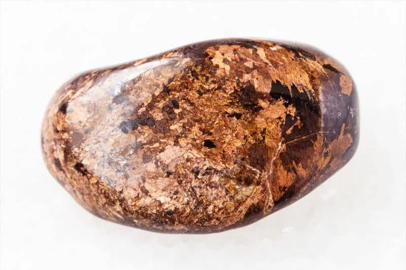 Pierre polie de bronzite sur fond blanc