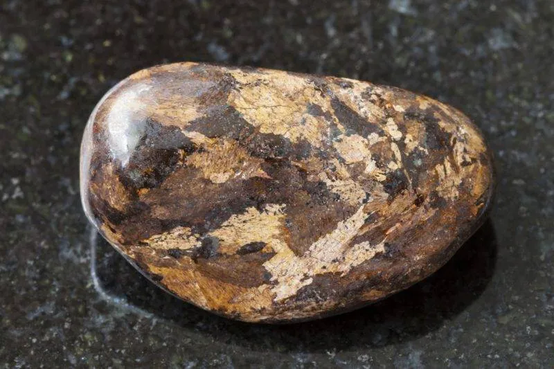 Pierre polie de bronzite sur fond de granit