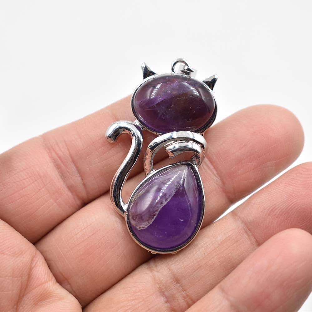 Lot de Dix Pendentifs Pierre Naturelle en Forme de Chat sur fond blanc dans une main