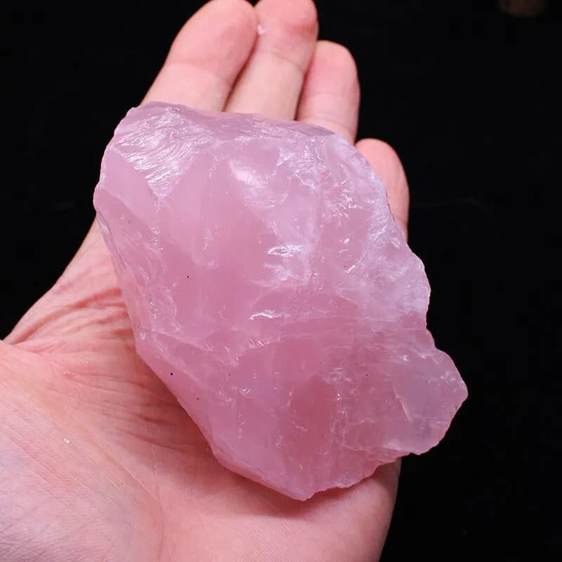Pierre Naturelle de Quartz Rose dans une main sur fond noir