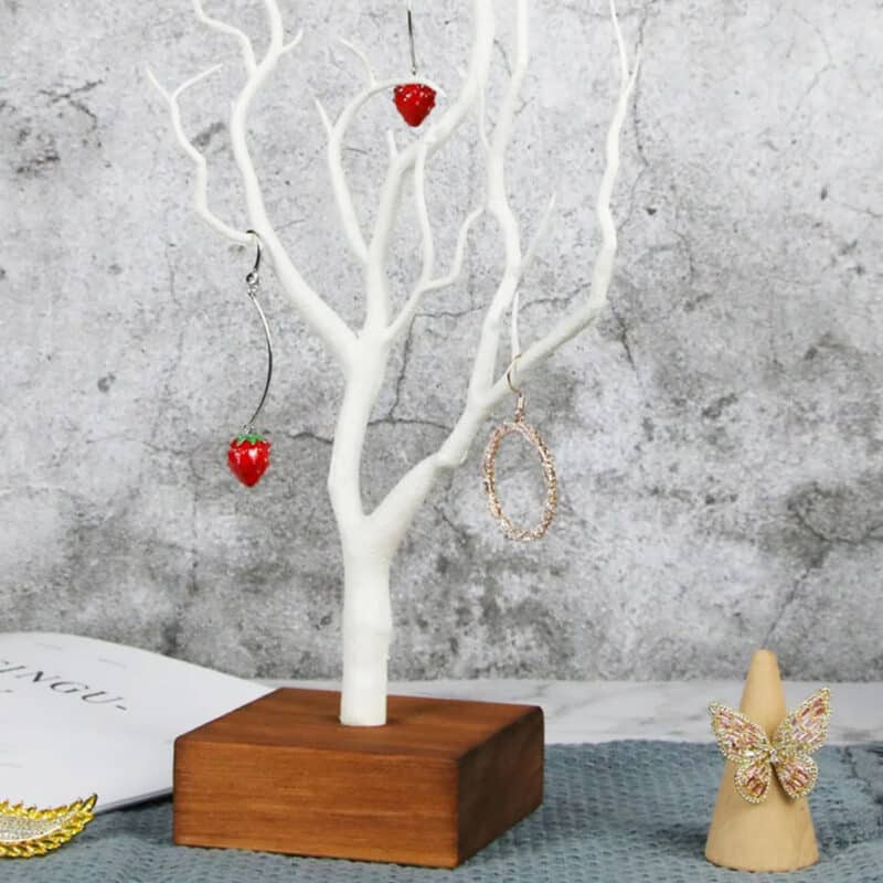 Arbre à Bijoux Blanc en Bois avec Socle sur un bureau avec des objets sur fond gris